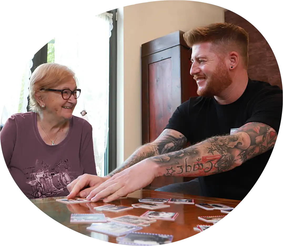 Sympathischer Pfleger beim Memory-Spielen mit einer Seniorin - beide Lachen herzlich