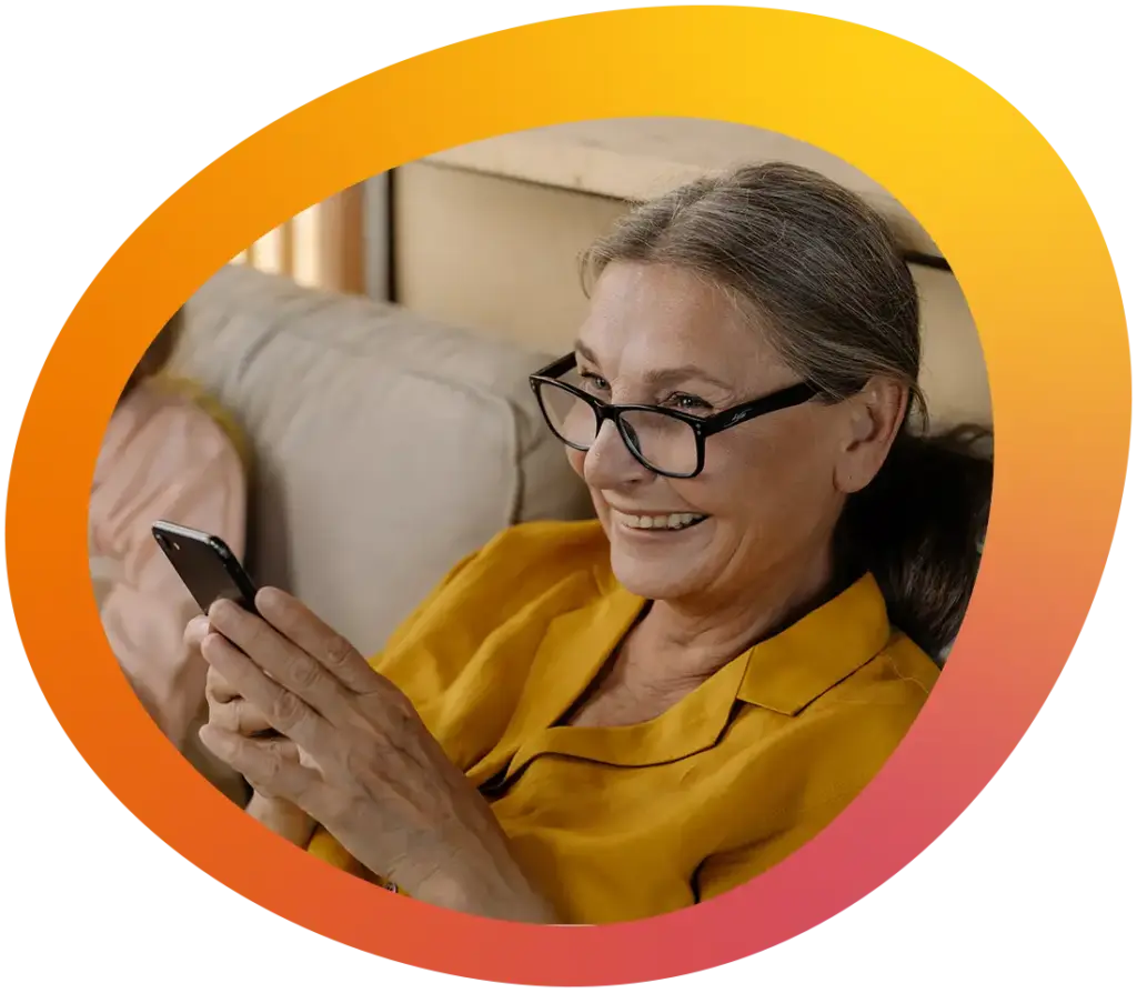 Eine fröhliche Seniorin schaut sich ein Video auf ihrem Smartphone an und lacht herzlich