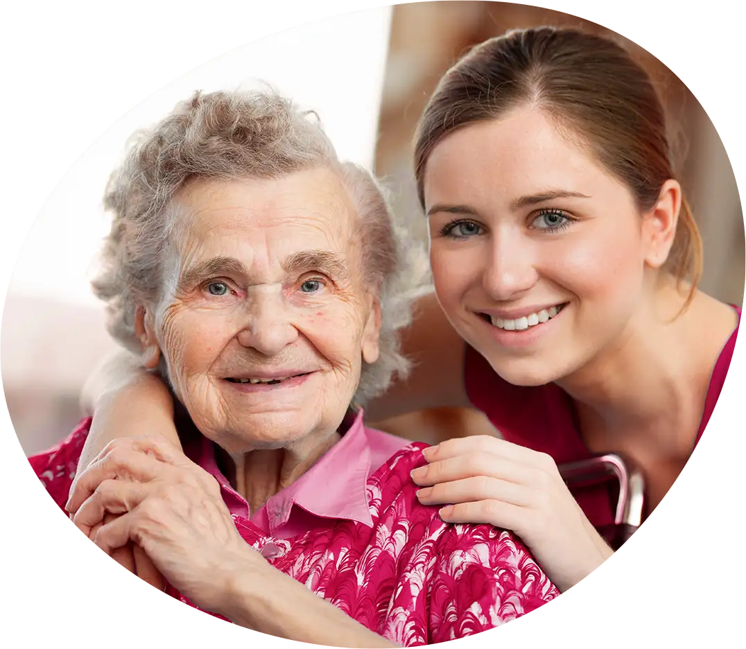Eine junge Pflegekraft umarmt eine glückliche Seniorin liebevoll