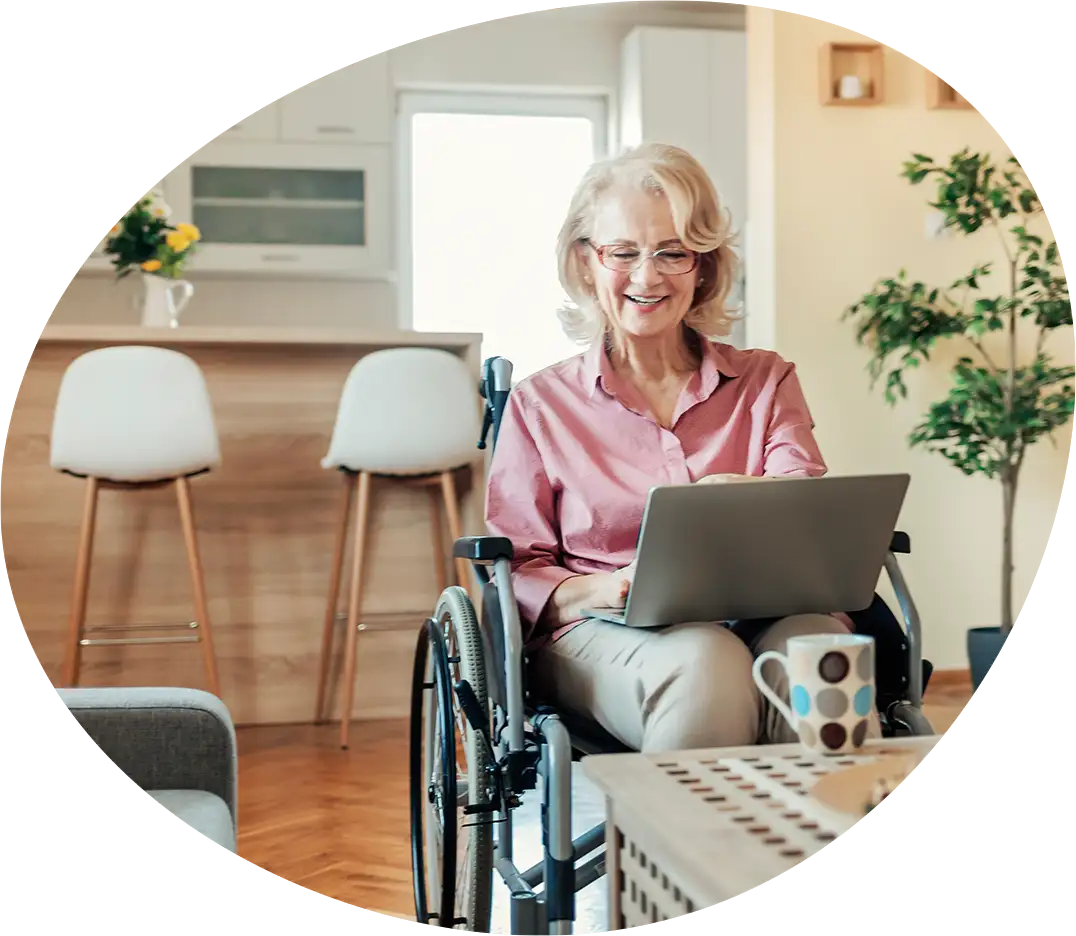 Ältere Dame im Rollstuhl sitzt motiviert am Laptop