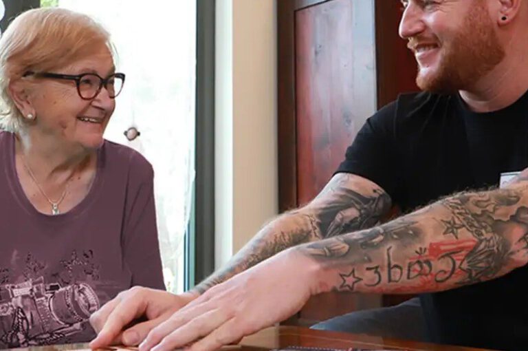 Betreuer spielt in der Tagespflege Memory mit einer Seniorin, beide lachen herzlich